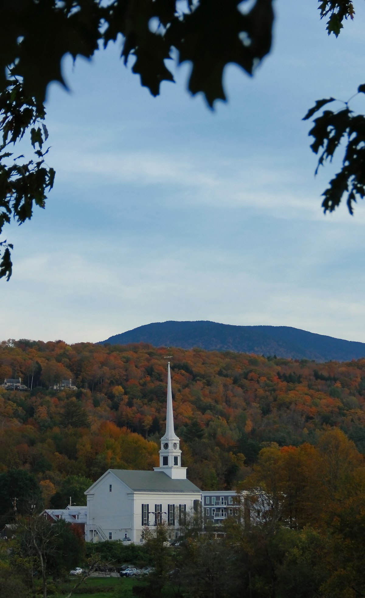 White church steeple rising above autumn foliage in a quaint New England village — a scene typical of small Vermont towns like Jamaica